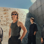 Band Don Broco with grey wall behind them and sky